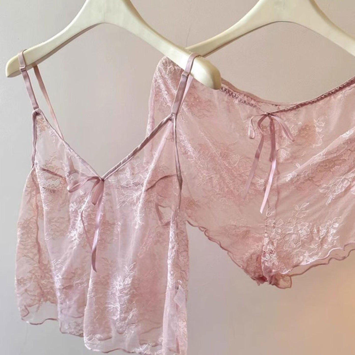Pink lace lingerie set on a hanger against a neutral background